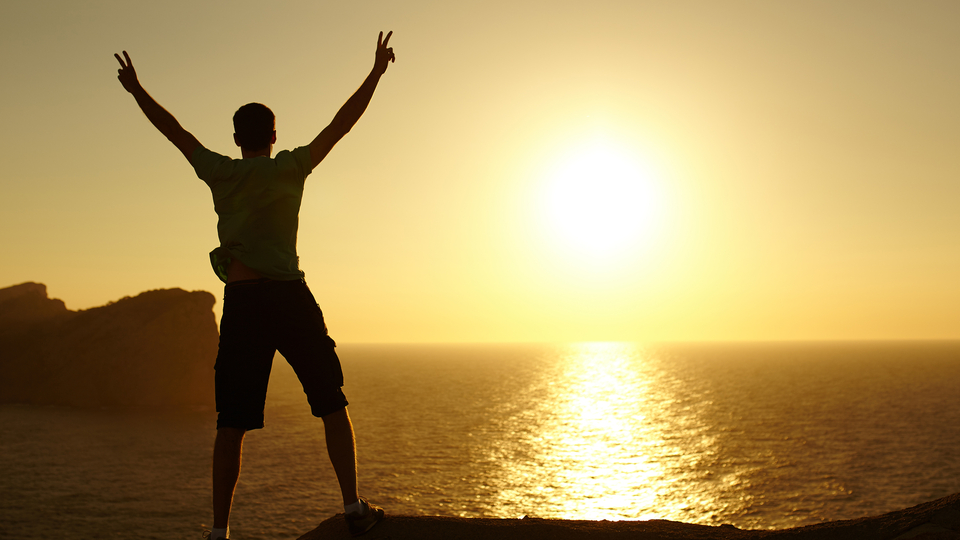 a man standing on a beach with his arms raised