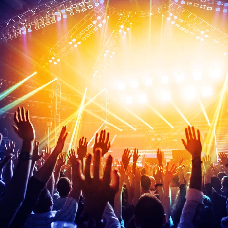 a crowd of people with their hands up in the air in front of a bright light