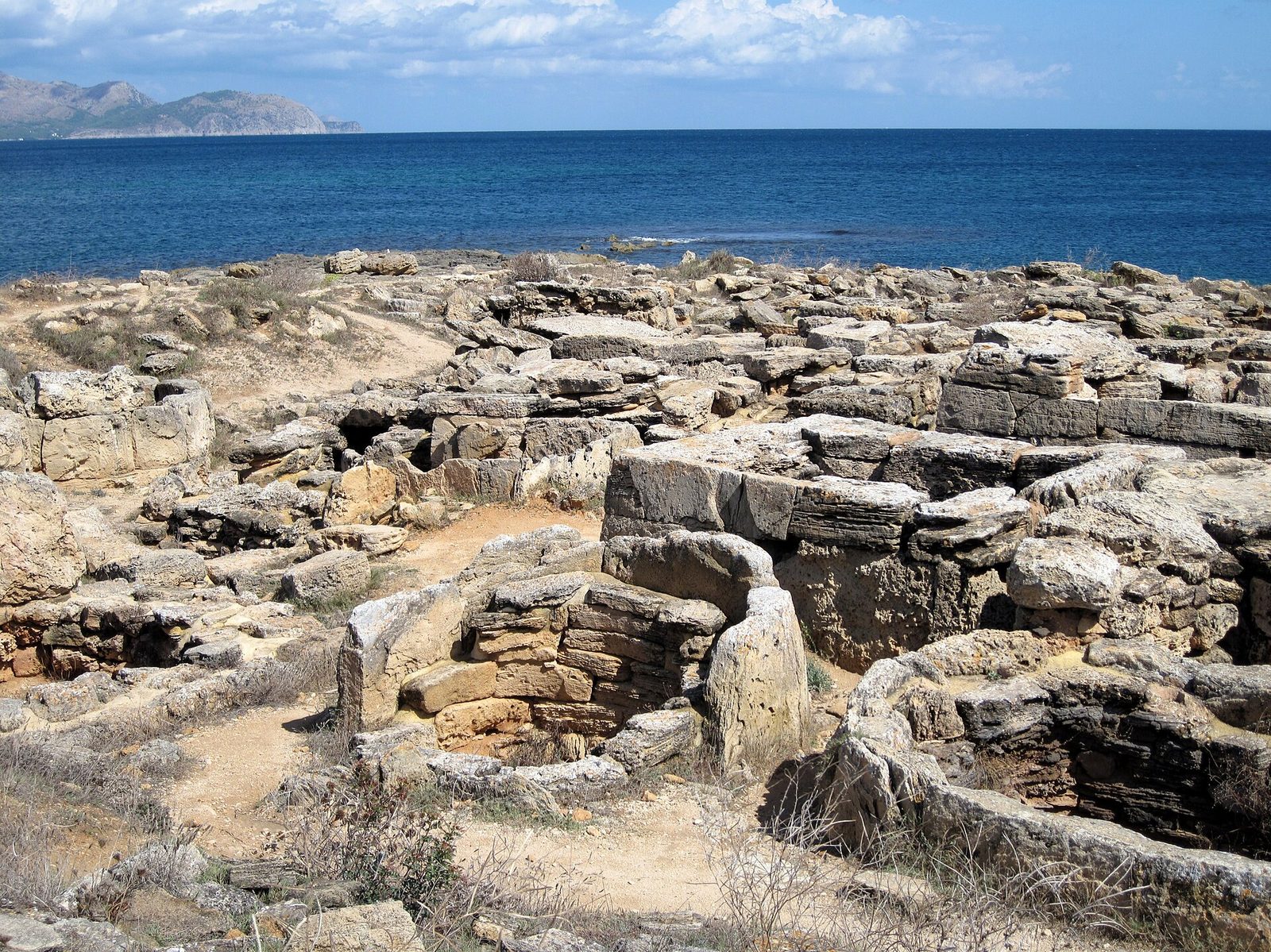 Tombes basses de la nécropole de Son Real au bord de la mer, péninsule d’Alcúdia au loin
